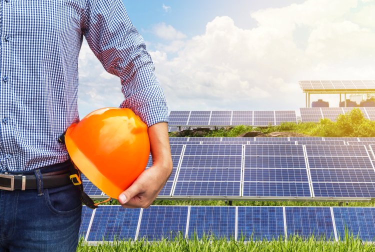 Tech with helmet in front of solar panels